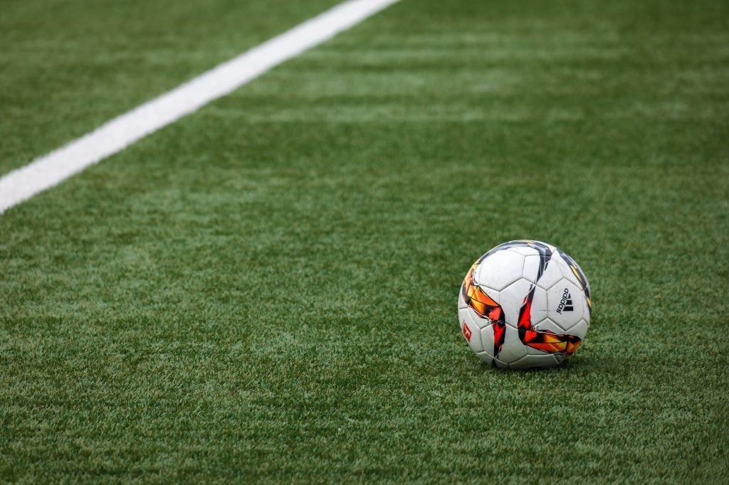 Soccer ball resting on vibrant green grass near a white sideline on the field.